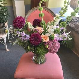 Mixed floral arrangement in a clear glass vase with pink, purple, white, and peach blooms