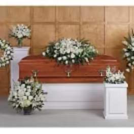 White funeral floral arrangements around a casket in a room