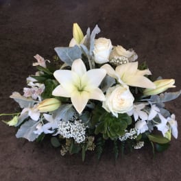 White lilies and roses arranged with pale blue foliage