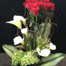 Tall arrangement of red roses and white calla lilies with green hydrangea