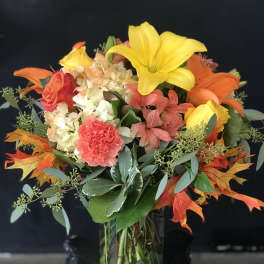 Bouquet of lilies, roses, hydrangea, and carnations in a glass vase