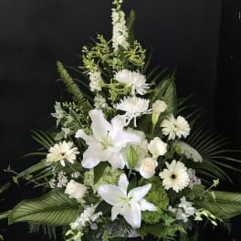 White floral arrangement with lilies, daisies, and roses in a dark vase