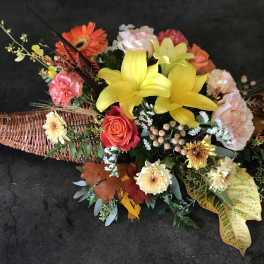 Colorful floral arrangement in a woven basket with yellow lilies and orange gerberas