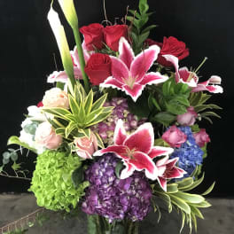 Mixed bouquet with red roses, pink lilies, and hydrangeas in a glass vase