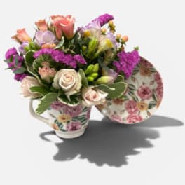 Floral arrangement in a floral teacup with pink and lavender blooms