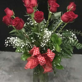 Bouquet of red roses in a glass vase with a red polka-dot ribbon