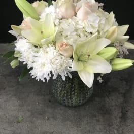 White lilies and pale roses in a textured glass vase