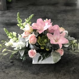 Pink and white floral arrangement in a white rectangular container