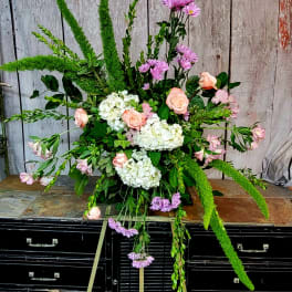 Large floral spray with pink roses, white hydrangeas, and purple blooms