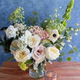 White and blush roses in a glass vase with airy greenery