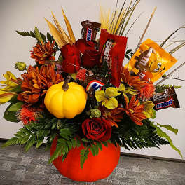 Pumpkin-shaped floral arrangement with candy bars and orange flowers