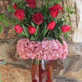 Red roses and pink hydrangeas in a tall glass vase