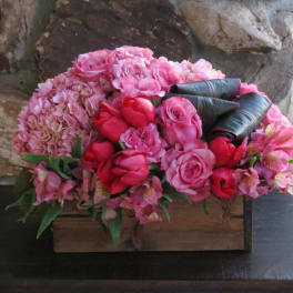 Pink floral arrangement in a wooden box with roses and hydrangeas