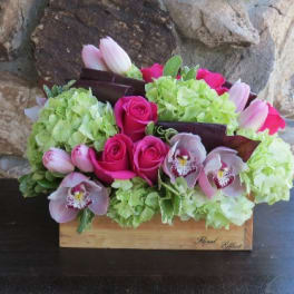 Bouquet of pink roses, tulips, and orchids in a wooden box