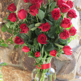 Bouquet of red roses in a clear glass vase with a red ribbon