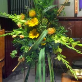 Tall floral standing spray with yellow blooms and long green leaves
