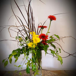 Tall vase arrangement with yellow calla lilies and red gerbera daisies