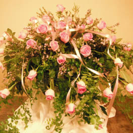 Large arrangement of pink roses with trailing greenery and ribbon