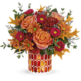 Orange and pink floral arrangement in a patterned vase