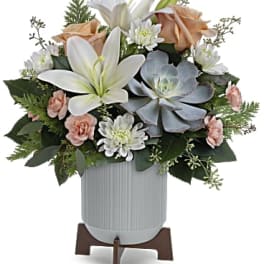 White lilies and peach roses arranged in a vase with daisies and succulents