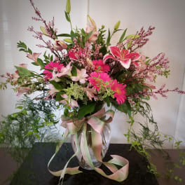 Pink and white mixed flowers in a clear glass vase with a ribbon
