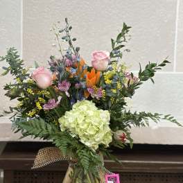 Mixed bouquet in a glass vase with pink roses and a green hydrangea bloom