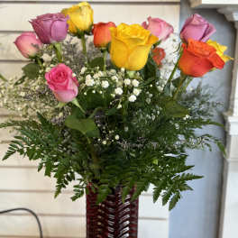 Mixed roses in a red glass vase with baby's breath