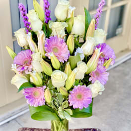 Pink gerbera daisies and white roses in a clear glass vase