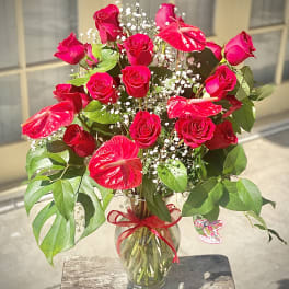 Red roses and anthuriums in a glass vase with baby's breath