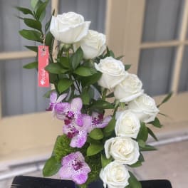 White roses and purple orchids in a square vase