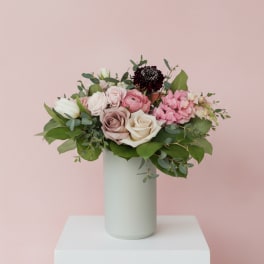 Pink and white rose bouquet in a tall pale vase