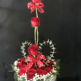Heart-shaped rose arrangement in a white basket with red bows