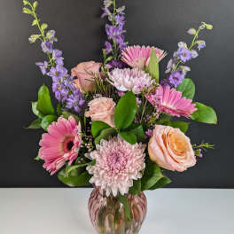 Pink and lavender flowers arranged in a glass vase