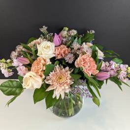 Pastel bouquet of roses, carnations, and chrysanthemums in a clear glass vase