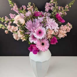 Pink and lavender flowers arranged in a white vase