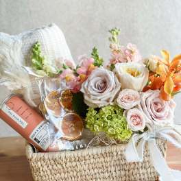 Flower and gift basket with pastel roses, hydrangeas, and snacks