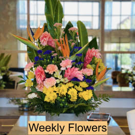 Tall mixed flower arrangement in a gray vase with bright tropical blooms