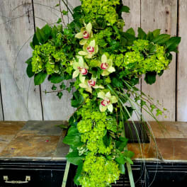 Green floral cross with orchids and hydrangeas on a stand