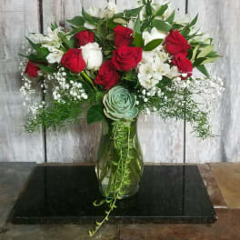 Red and white roses in a glass vase with baby’s breath