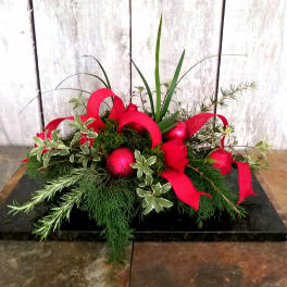 Low holiday arrangement with red ribbon loops and red ornaments
