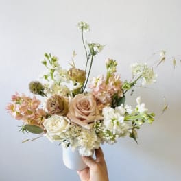 Pastel bouquet of roses and white blooms in a white vase