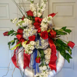 Large floral wreath with red roses and white blooms on a stand