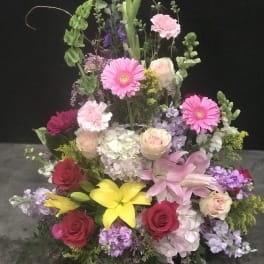 Tall mixed flower arrangement with pink, yellow, red, and lavender blooms
