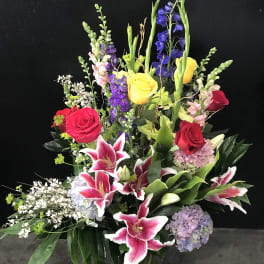 Tall mixed bouquet with roses, lilies, and hydrangeas in a glass vase