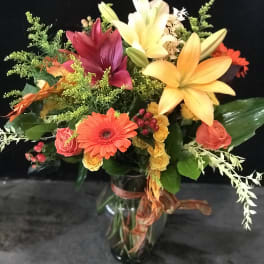 Mixed bouquet of lilies, gerbera daisies, and roses in a glass vase