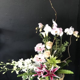 Mixed floral arrangement in a wicker basket with pink and white blooms