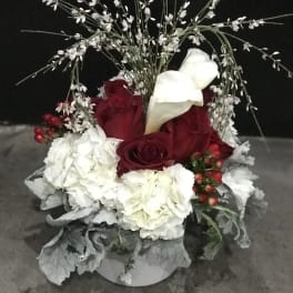 Red roses and white calla lilies in a white container with white filler flowers