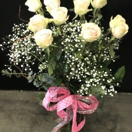 Bouquet of pale yellow roses with baby's breath in a glass vase and pink ribbon