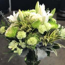 White lilies and green carnations in a glass vase