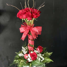 Tall bouquet of red roses with a polka-dot ribbon on a white base